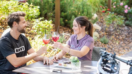 Couple toasting with drinks at outdoor garden cafe
