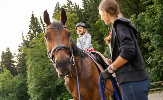First happiness of riding / 3 nights Child wearing helmet riding horse, woman leading horse in forest