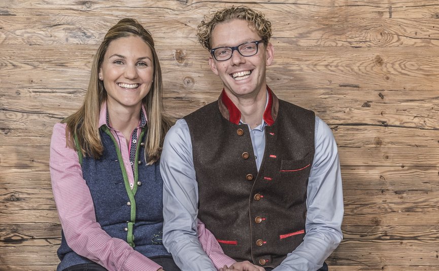 Fröhliches Paar sitzt vor Holzwand und hält Hände