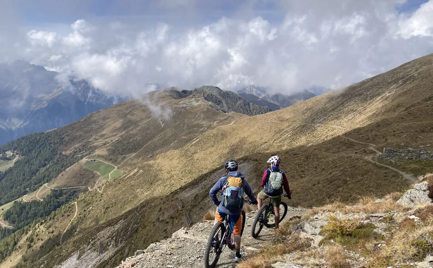Hotel Innerhofer *** © Hotel Innerhofer Zwei Mountainbiker fahren auf einem Bergpfad mit Blick auf bewölkte Berge