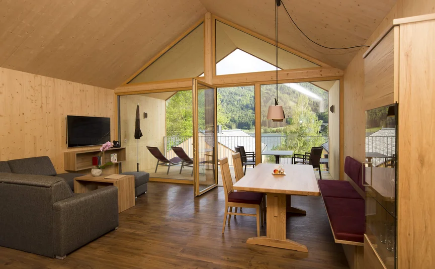 Modernes Wohnzimmer mit Holzmöbeln und Blick auf Terrasse und Berge