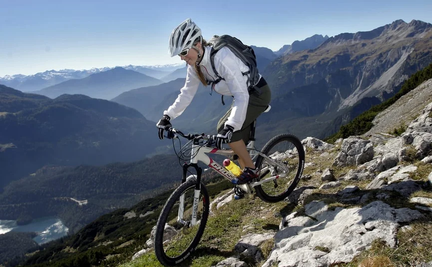 Woman mountain biking on rocky trail with alpine mountain views