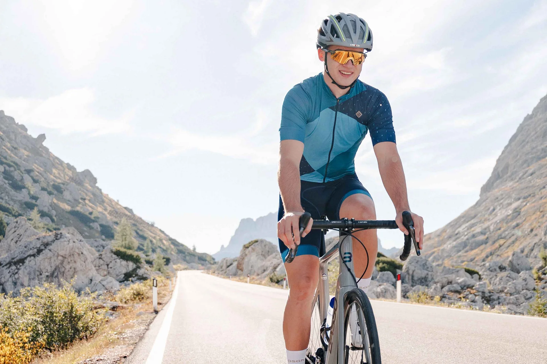 Mann fährt Rennrad auf Bergstraße bei sonnigem Wetter
