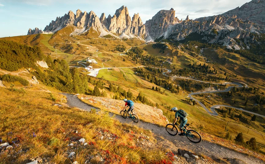 Two mountain bikers on trail in mountainous landscape with rocky peaks
