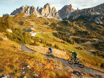 Two mountain bikers on trail in mountainous landscape with rocky peaks
