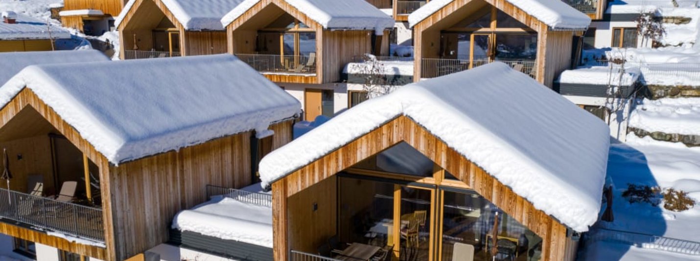 Besneeuwde houten chalets in een winters resort omgeven door besneeuwde bergen