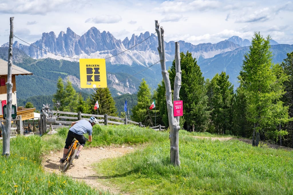 Mountain biker riding a trail with mountain scenery at Brixen
