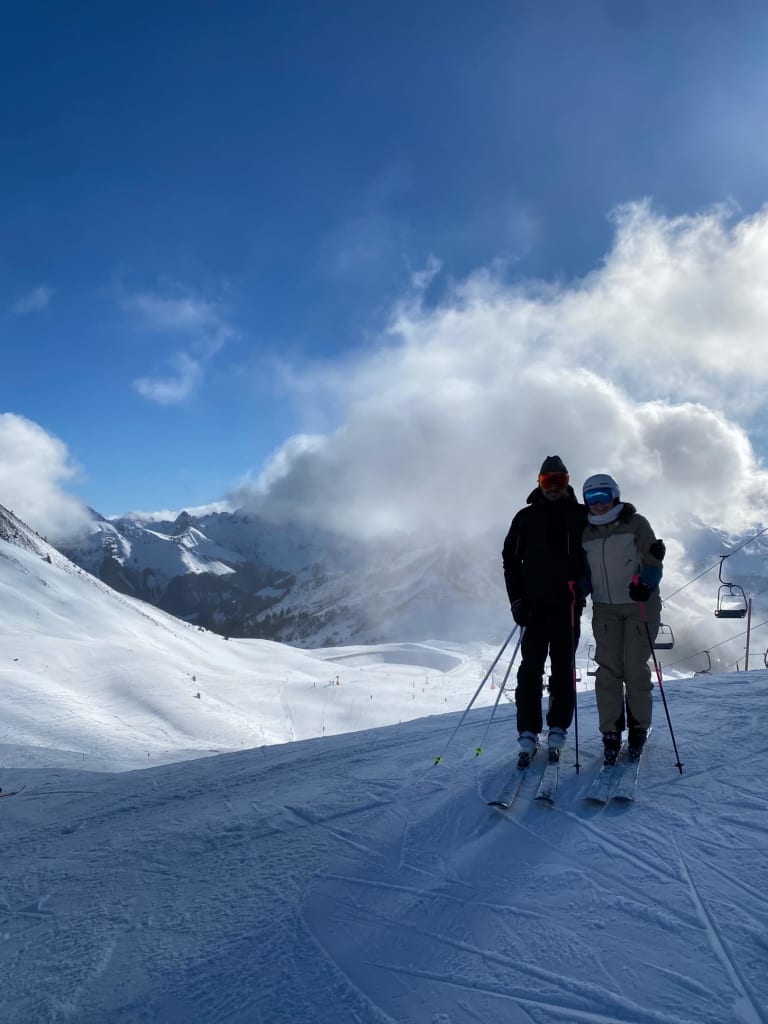 Twee skiërs staan op besneeuwde berghelling onder bewolkte lucht