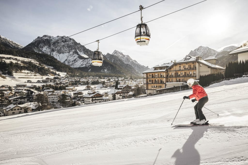 Skier in red jacket skiing near cable cars in snowy mountain village