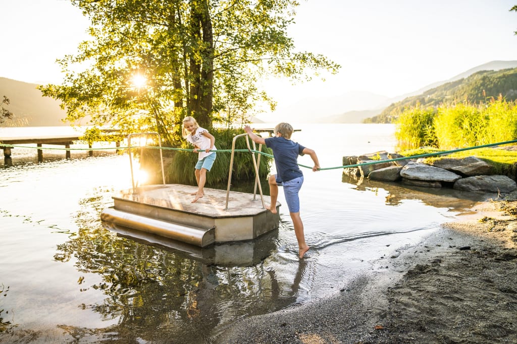 Familienhit im Früh-& Spätsommer 7 Nächte Kinderen spelen op een kleine veerboot bij het meer tijdens zonsondergang