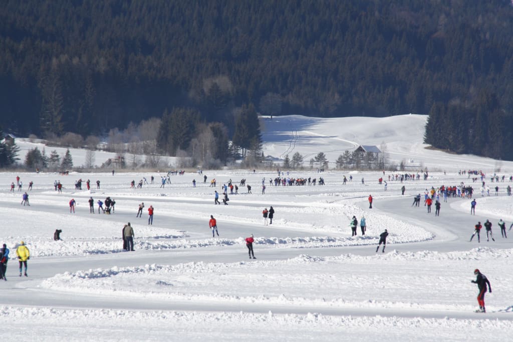 "Februar-Auszeit für aktive Genießer" Viele Menschen beim Schlittschuhlaufen auf einer zugefrorenen Bahn im Winter