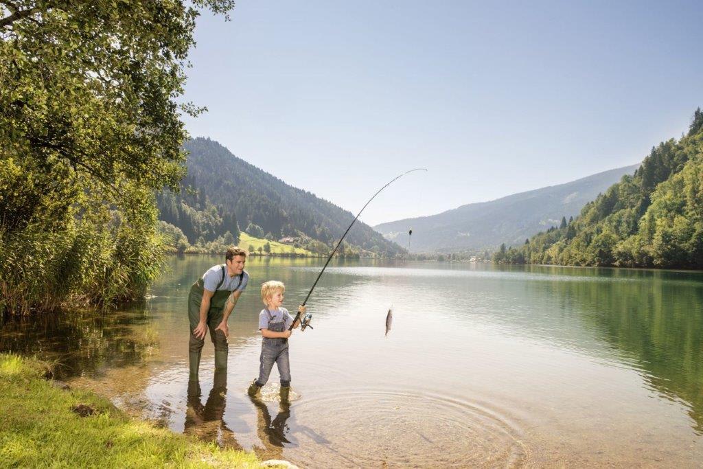 Vater und Sohn angeln an einem ruhigen Bergsee
