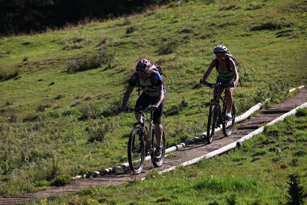 Herbst-Bikewochenende Zwei Radfahrer fahren auf einem schmalen Weg durch eine grüne Wiese