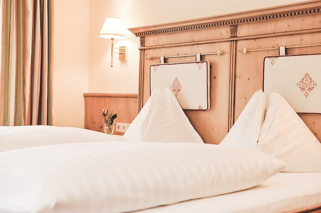 Doppelzimmer Standard Gemütliches Bett mit weißen Kissen und Holzkopfteil in einem Hotelzimmer