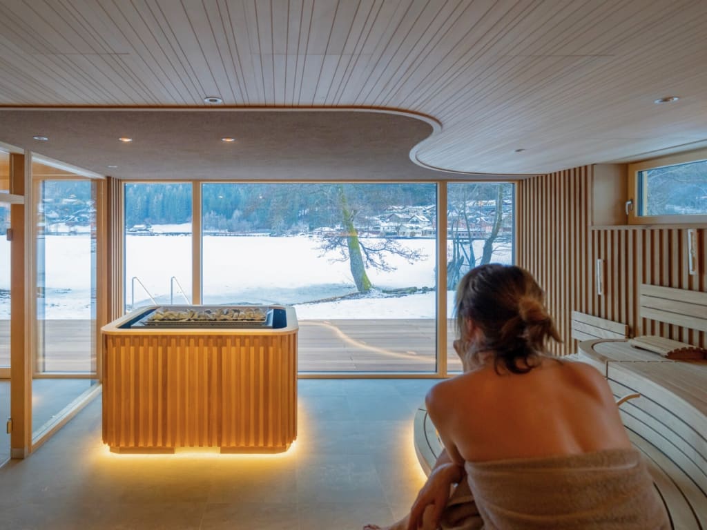 Brennseehof Saunatage Frau genießt Sauna mit Blick auf verschneite Landschaft durch große Fenster