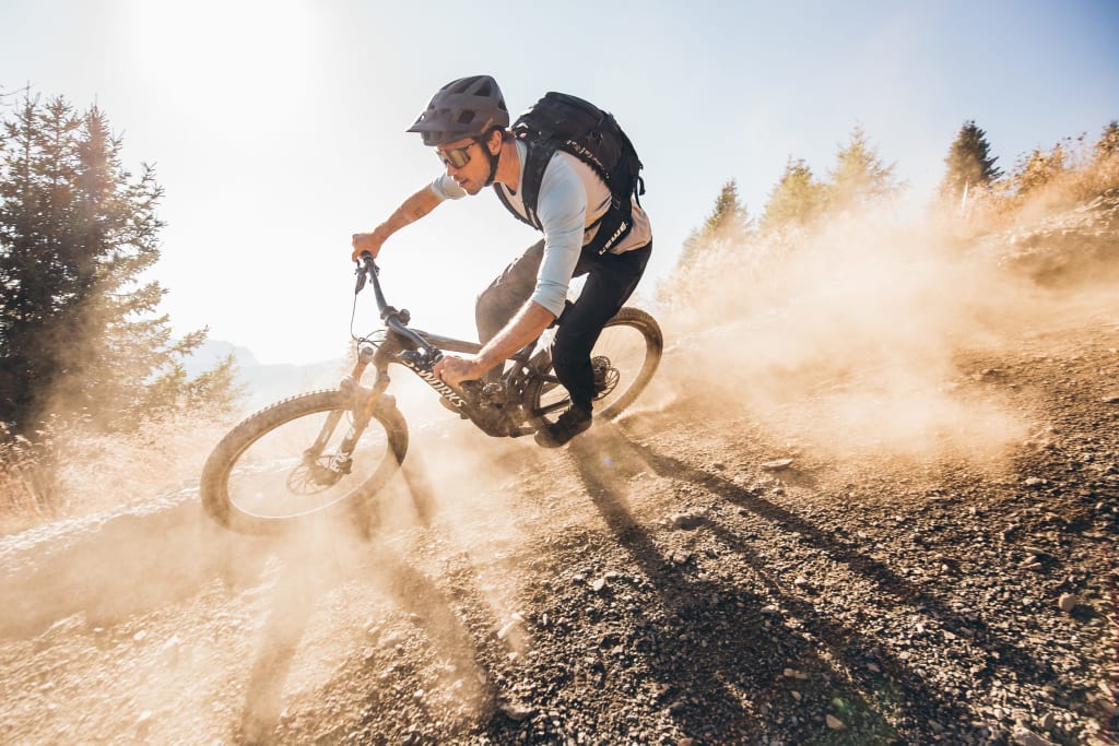 Mountain biker riding down dusty slope on a sunny day