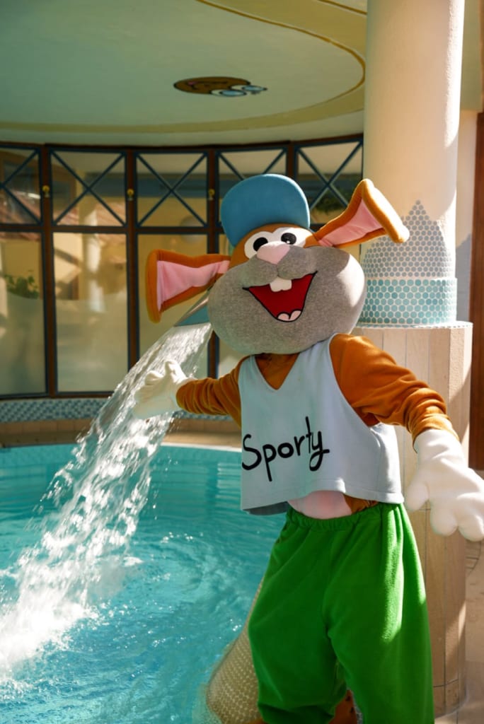 Sporty’s SCHWIMMtage Person im Hasenkostüm neben einem Pool mit Wasserfontäne
