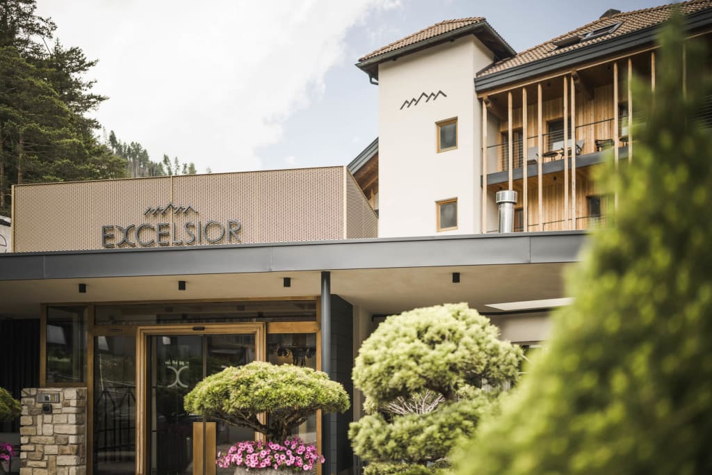 Entrance of Hotel Excelsior with trees and mountains in the background