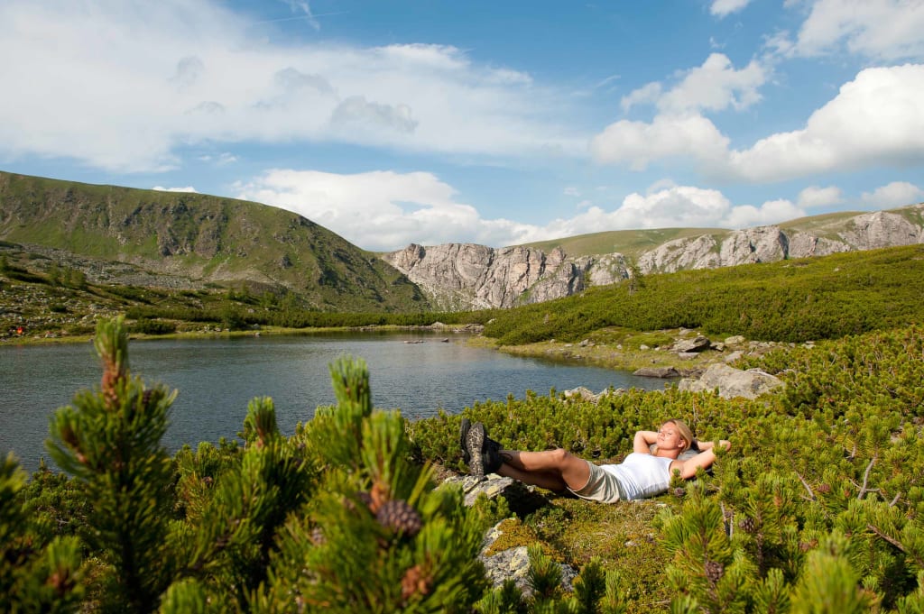 Wanderlust in den Nockbergen Vrouw ontspant bij een meer omgeven door bergen en groene natuur