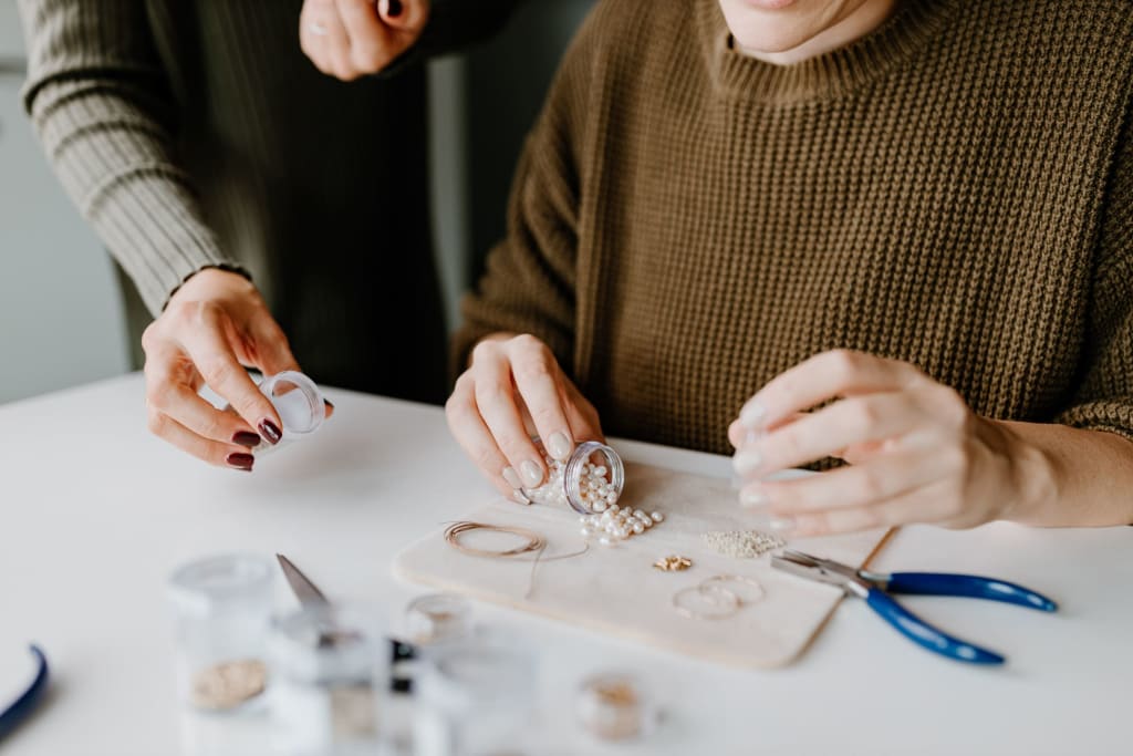 Yoga & Create - DEIN Wochenende am Weissensee Personen, die Perlen und Schmuckwerkzeuge auf einem Tisch arrangieren