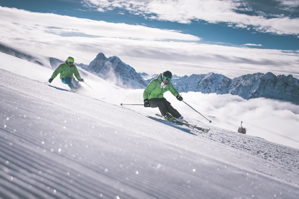 Zwei Skifahrer fahren einen schneebedeckten Hang in den Bergen hinunter