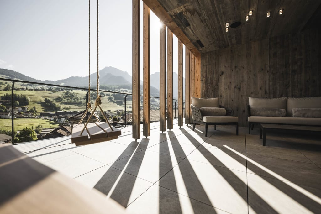 Modern balcony with wooden seats and swing overlooking mountains