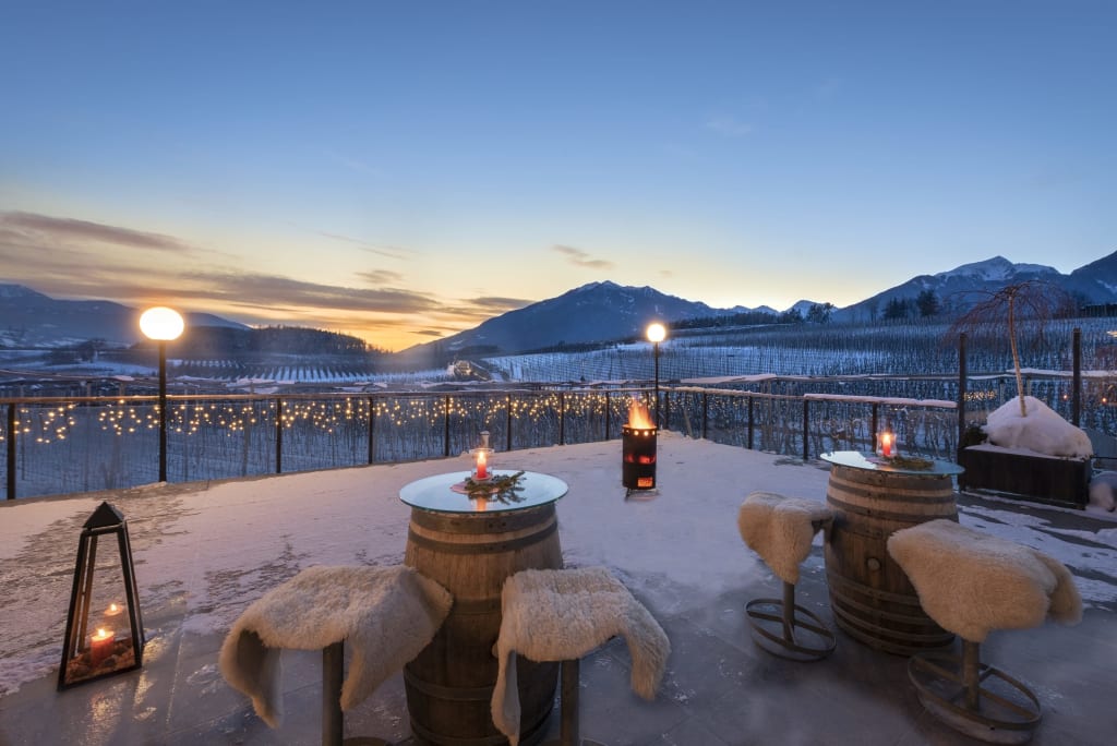 Winterterrasse mit Fässern als Tische und Schafsfell-Stühlen bei Sonnenuntergang