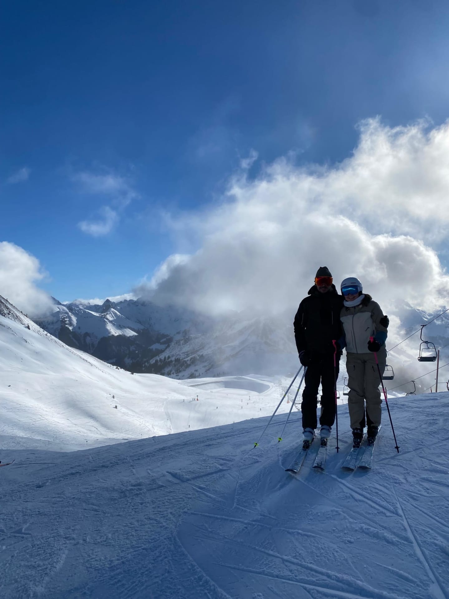 Two skiers on a snowy mountain under blue sky with clouds