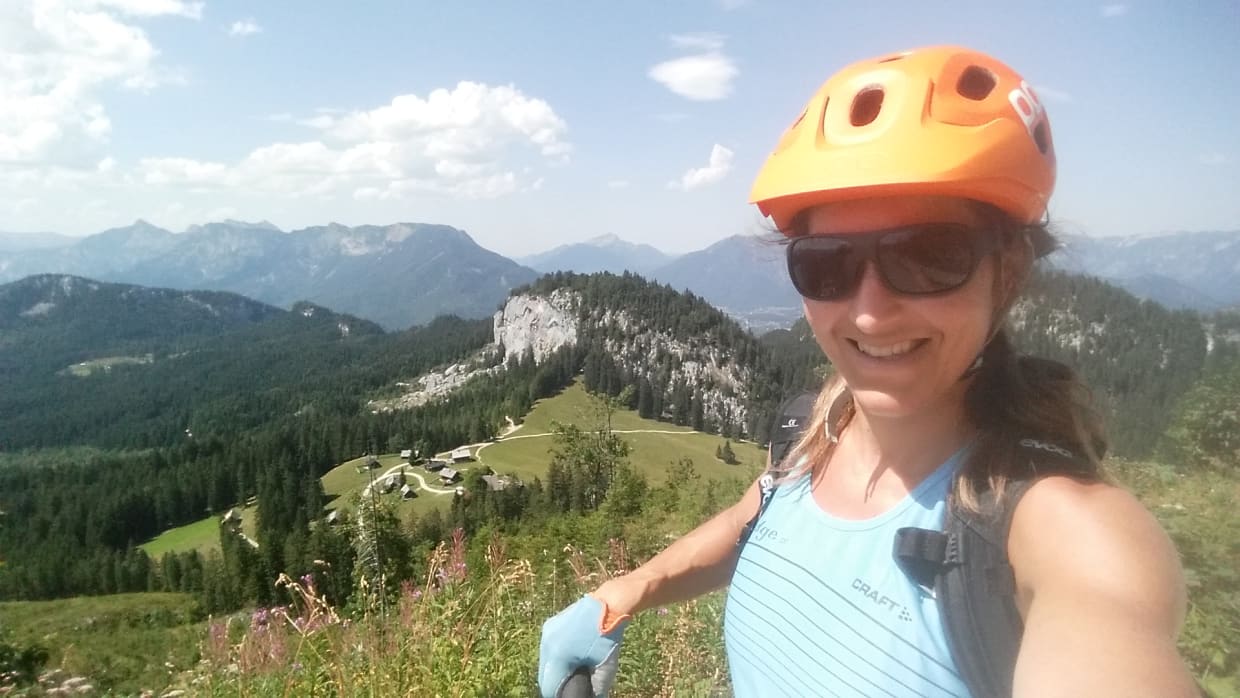 Berge-Seen-E-Bike-Package Frau mit Helm und Sonnenbrille macht Selfie in den Bergen bei Sonnenschein