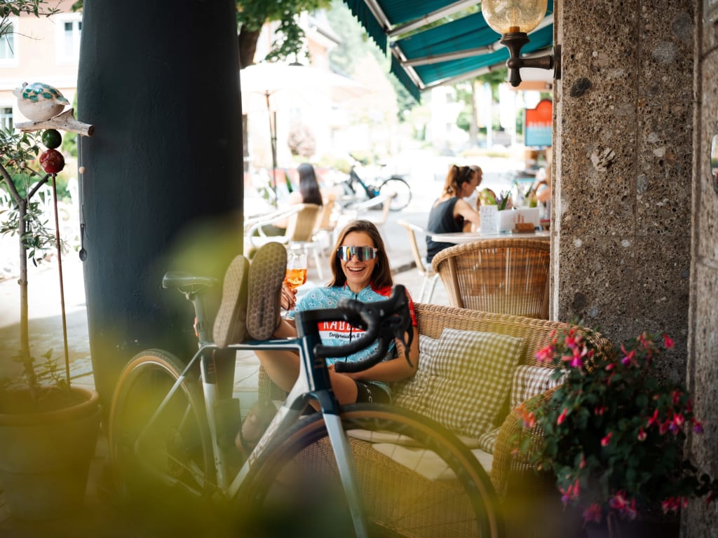Frau entspannt mit Fahrrad in Straßencafé