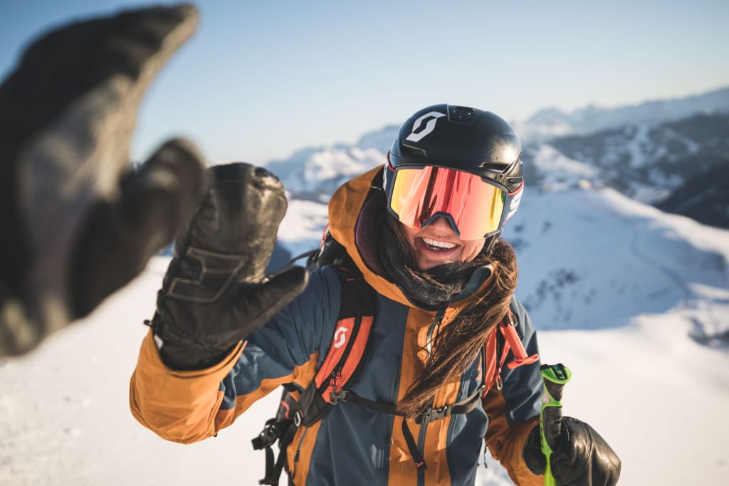 Skier wearing helmet and goggles giving high five in snowy mountain