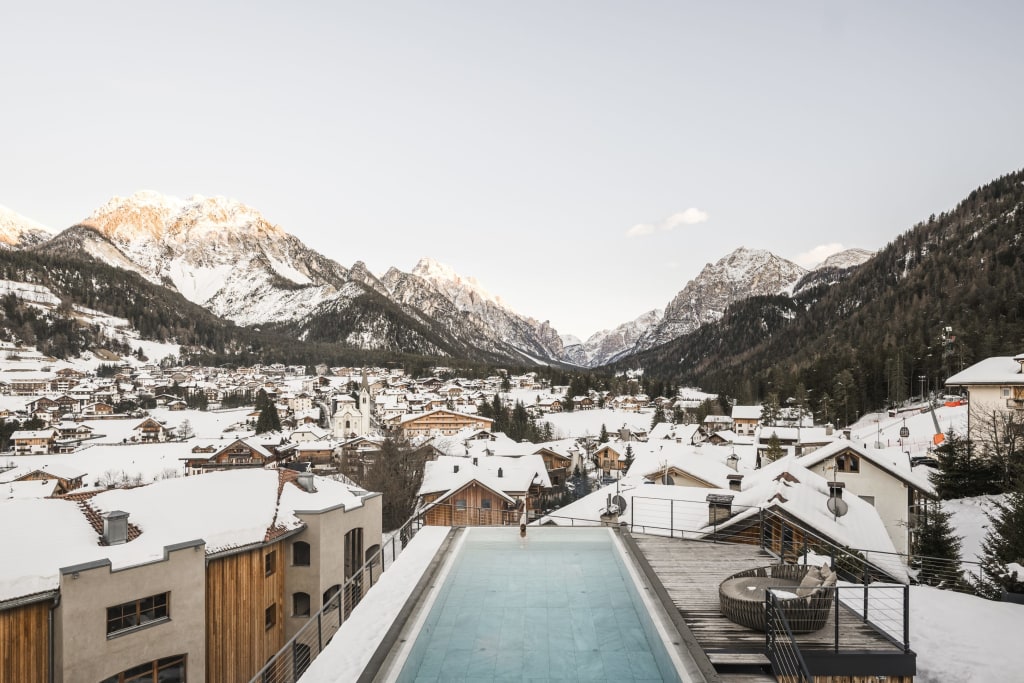 Snow-covered mountain town with pool and mountains in the background