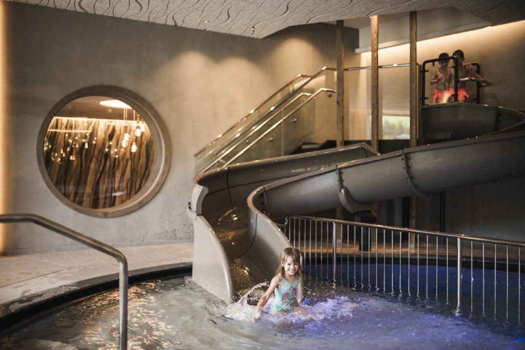 Child playing at the end of a water slide in an indoor pool