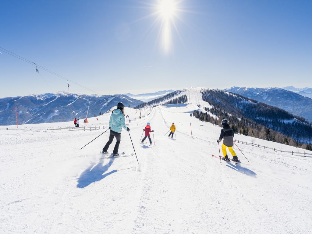 Skifahrer auf schneebedeckter Piste bei sonnigem Wintertag in den Bergen