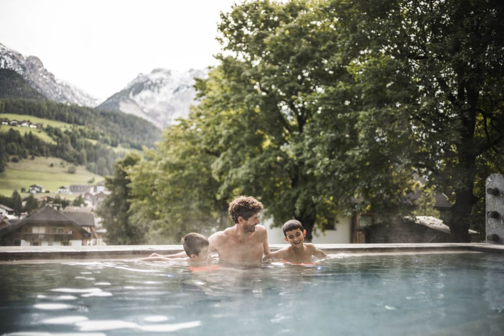 Father and two kids enjoying a hot pool with mountain view