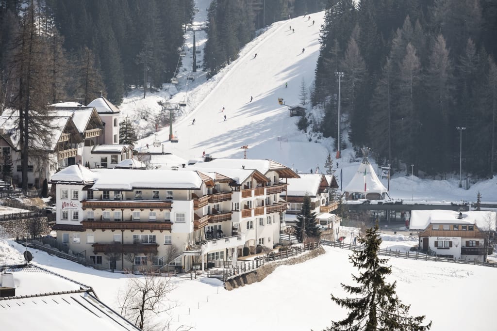 Sneeuwbedekt bergdorp met skiërs en stoeltjeslift in de winter