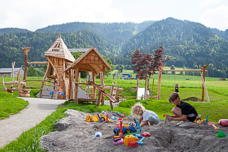 Children playing in sandbox at playground with mountain view