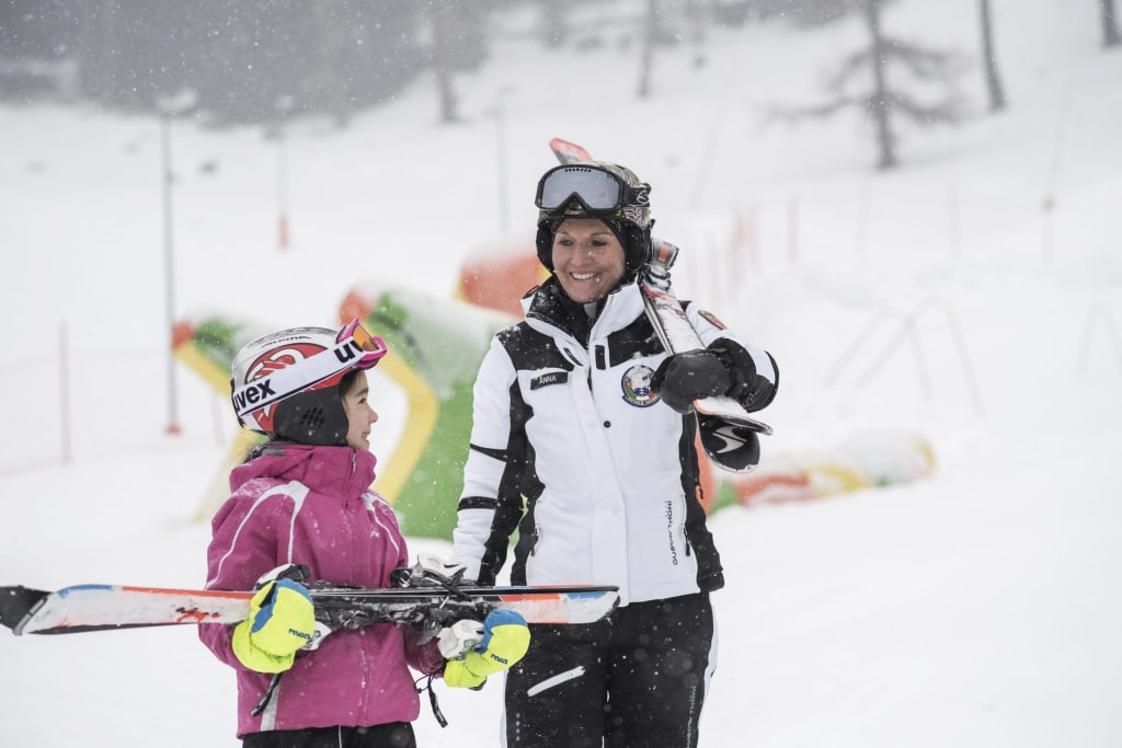 Volwassene en kind met ski's glimlachend in de sneeuw