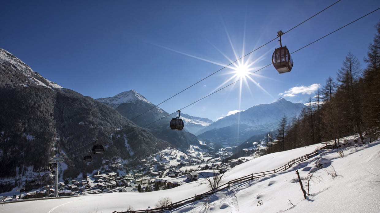 Cable car over snowy mountains and village on a sunny winter day