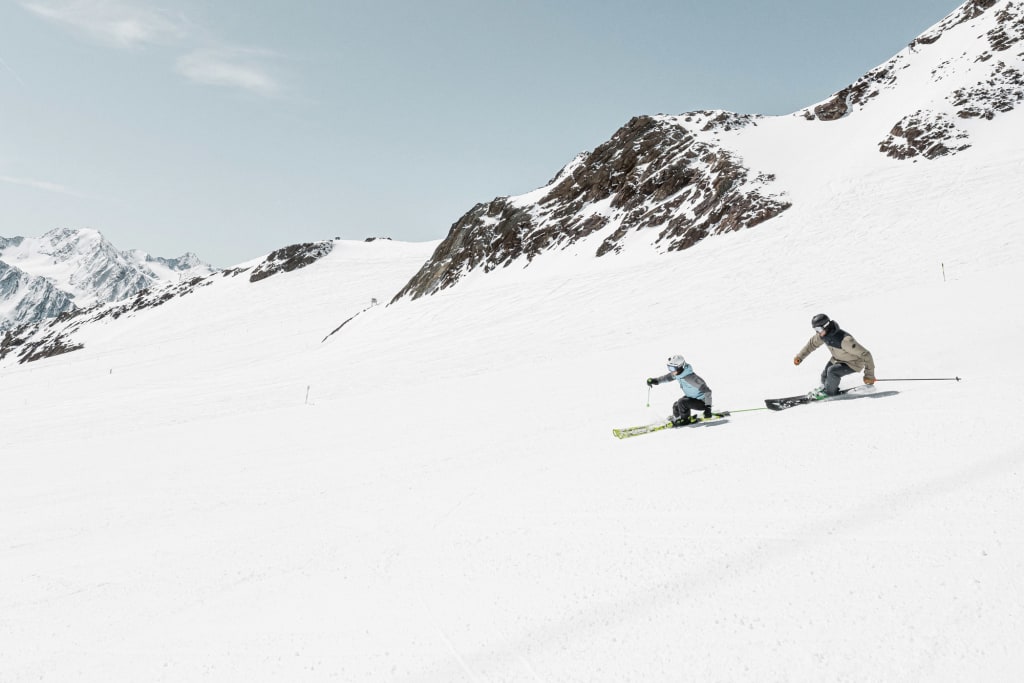 Two skiers skiing down a snowy mountain slope