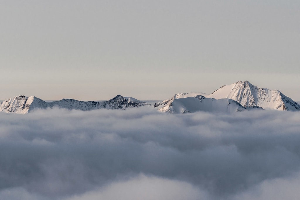 Snow-covered mountain peaks above a thick cloud layer