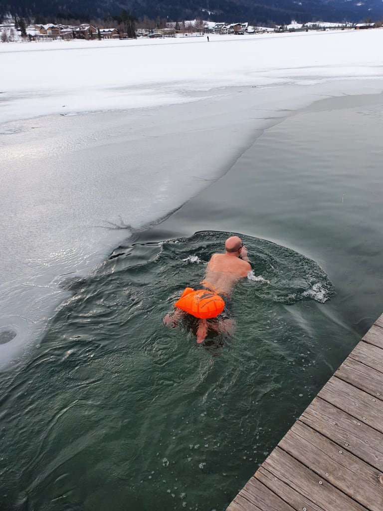 Atmen & Kälte – Das „coole“ volle Programm Mann schwimmt in eisigem Wasser neben zugefrorenem See