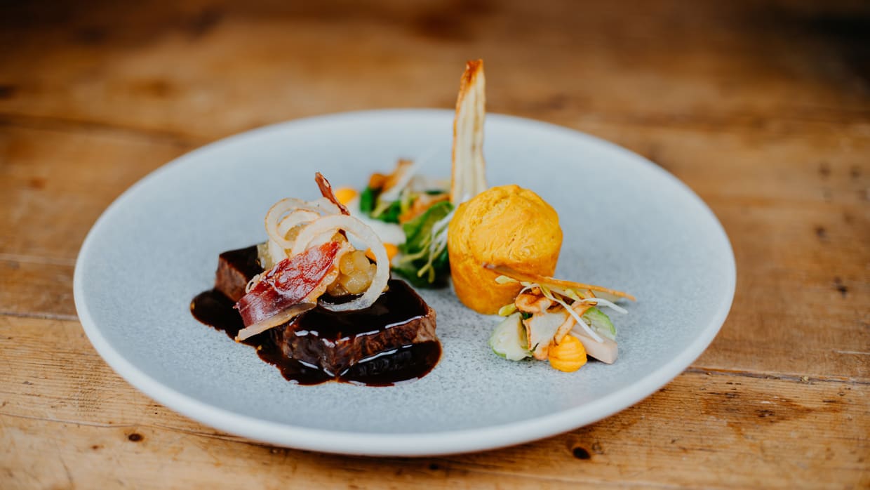 Elegant gerecht met vlees, saus, groenten en bijgerecht op een witte plaat
