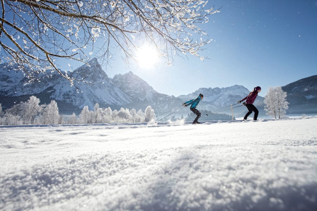 Twee mensen langlaufen in besneeuwde bergvallei onder heldere zon