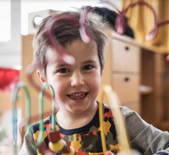 Lachende jongen speelt met kleurrijk educatief speelgoed binnen