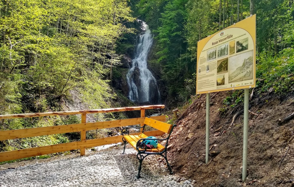 E-Mountainbike-Kurzurlaub Wasserfall in einem Wald mit Bank und Infotafel am Wanderweg
