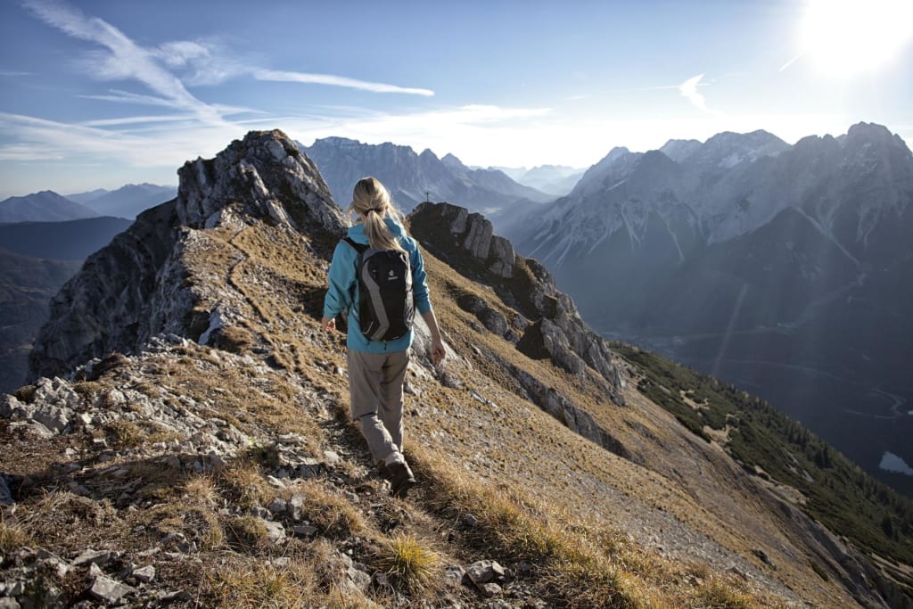 Woman hiking on narrow mountain trail with alpine mountain view