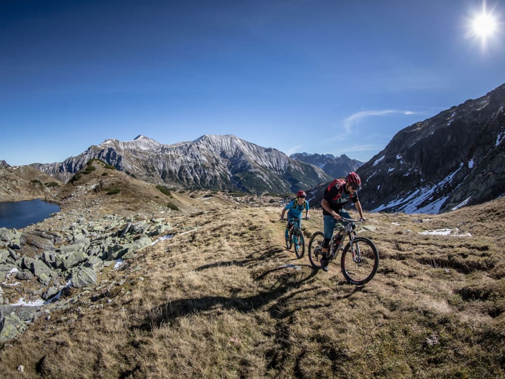 Zwei Mountainbiker fahren auf Bergweg bei sonnigem Wetter