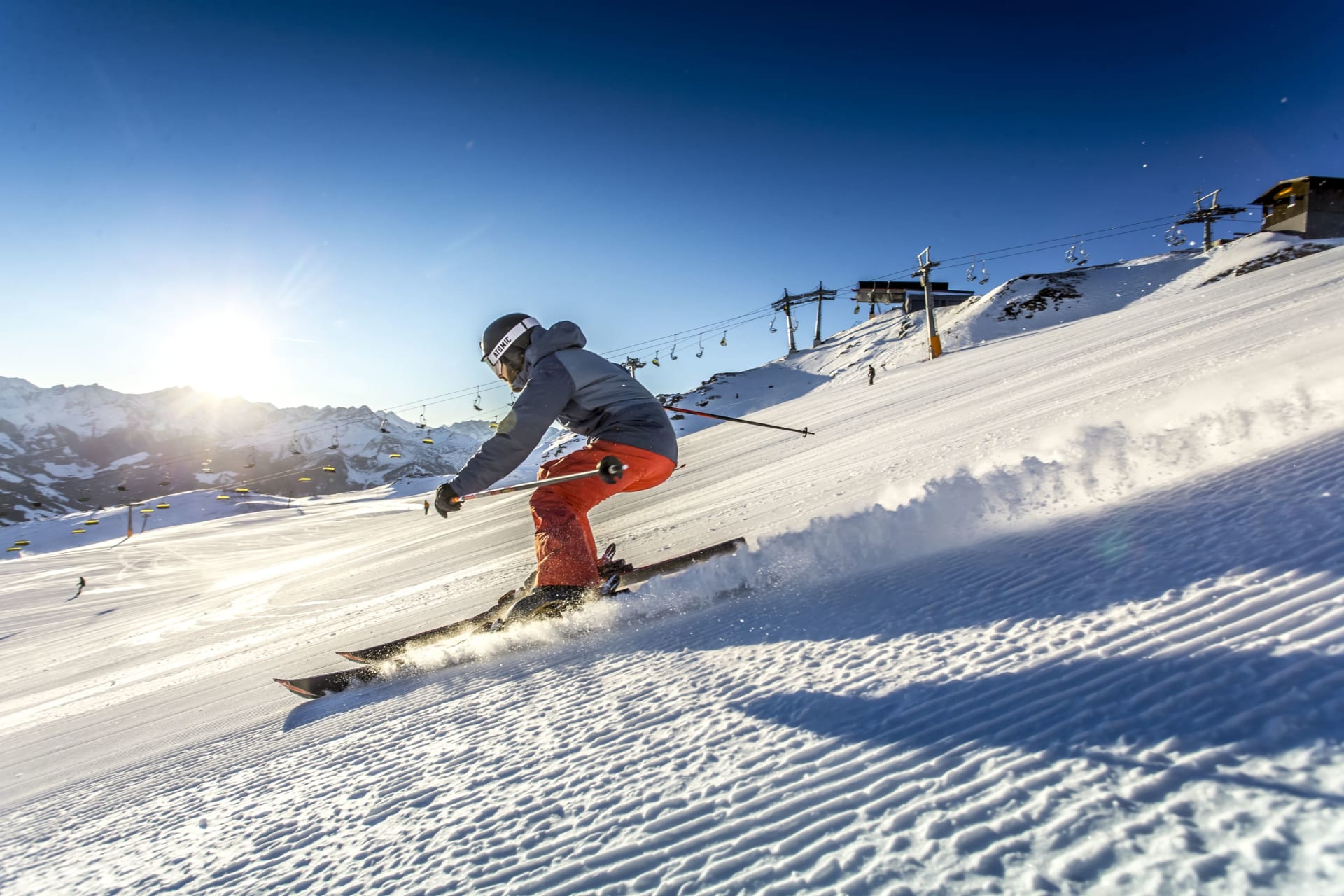Skifahrer fährt bei Sonnenschein die präparierte Piste hinunter