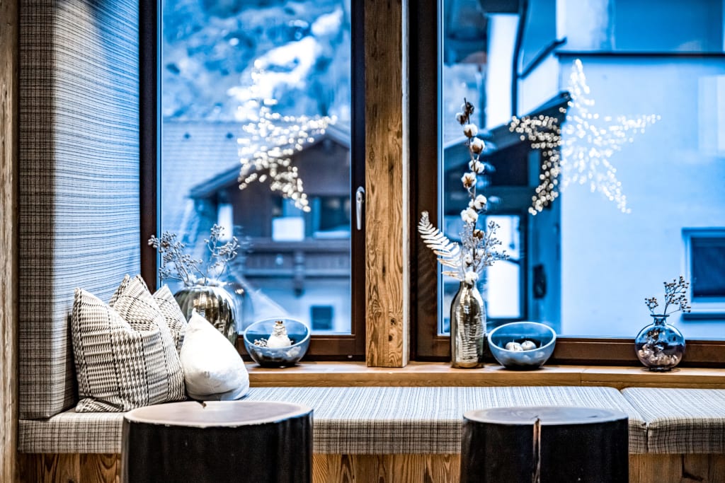 Cozy window seat with cushions and decorations by a wintery window